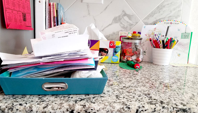 Messy pile of papers on a kitchen counter.