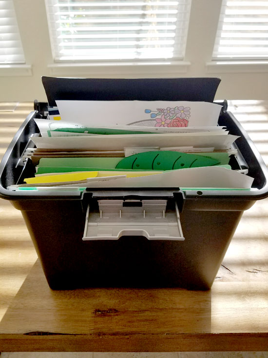 File box filled with kids artwork.