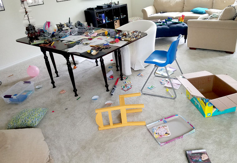Table covered in Lego, toys, and papers in a messy playroom - Hope for Moms with a Messy House