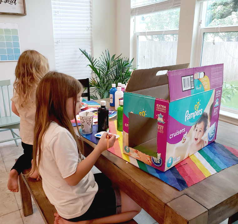 Girls making art creations with cardboard boxes.