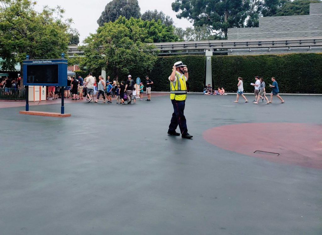 Disneyland Cast Member directing people to open lines.