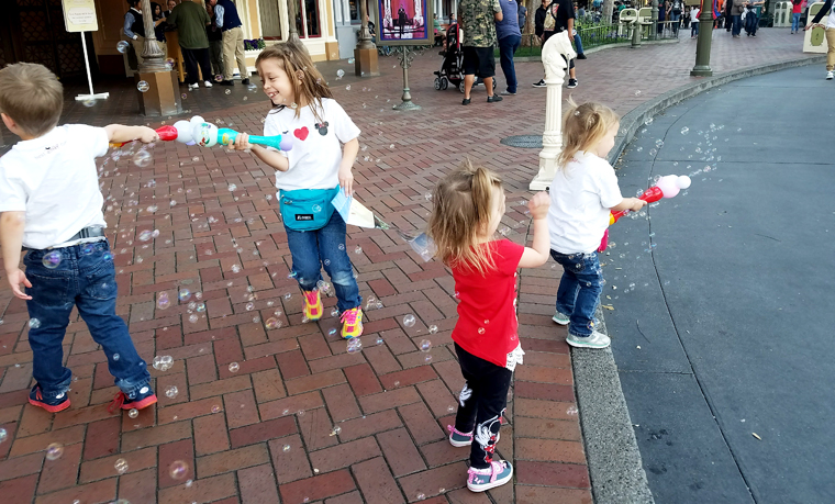 Children playing with bubbles on Disneyland's Main Street. One of our favorite Disneyland tip for families is to take "active" breaks.