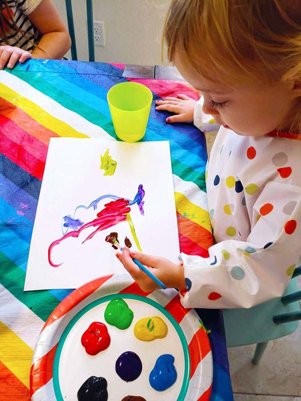Toddler painting at the kitchen table