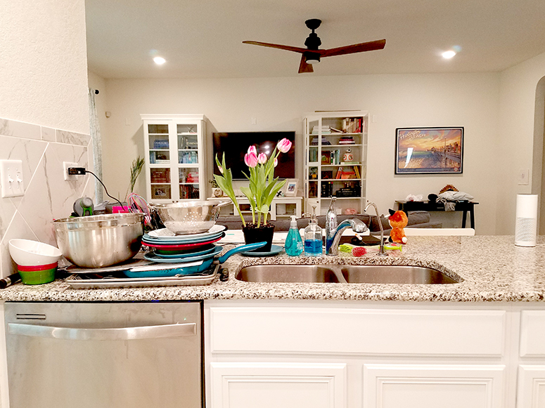 Kitchen sink with dishes piled beside it.