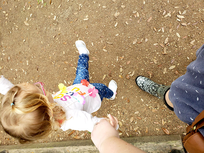 Mom holding hands with a toddler.