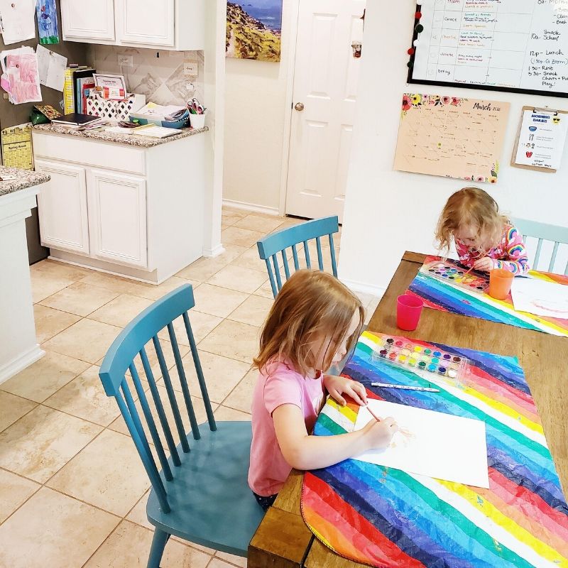 Two girls painting at the kitchen table